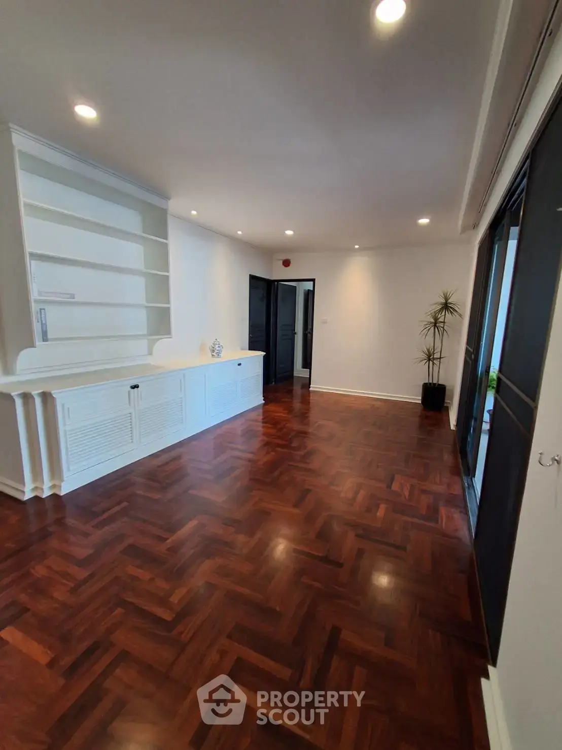 Spacious living room with elegant wooden flooring and built-in shelving, perfect for modern living.