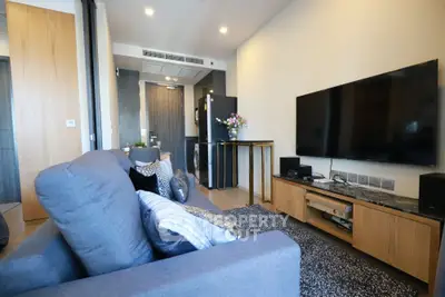 Modern living room with stylish decor and large flat-screen TV in a cozy apartment setting.
