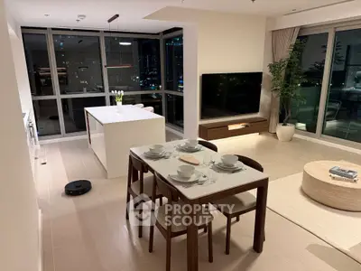 Modern open-plan living room with dining area and city view, featuring sleek furniture and large windows.