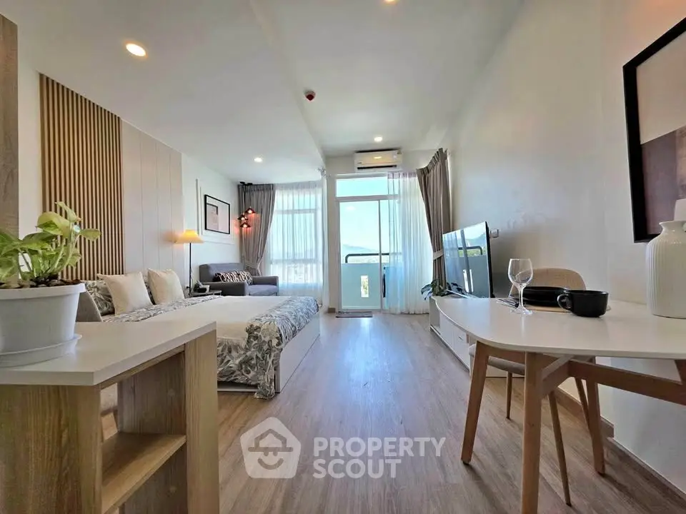 Modern studio apartment with stylish decor and natural light, featuring a cozy living area and a scenic balcony view.