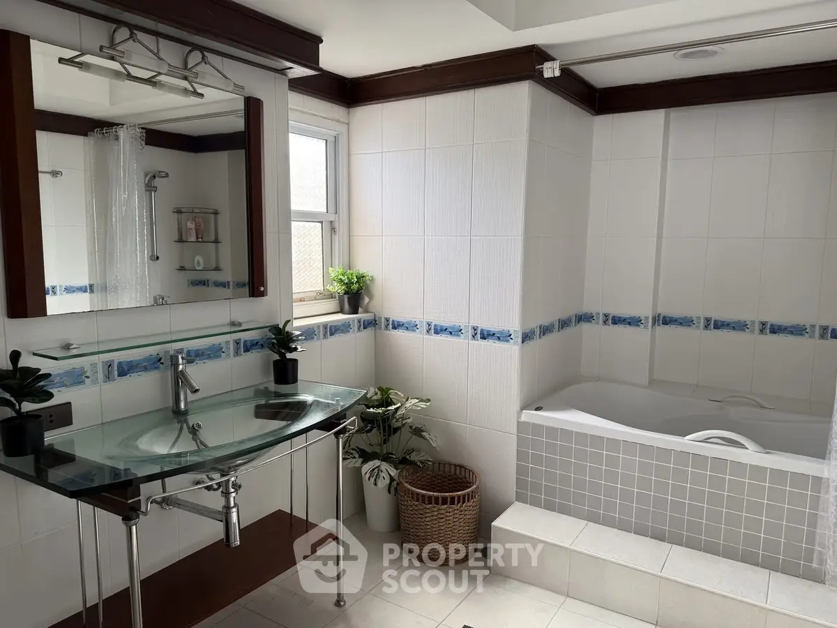 Modern bathroom with glass sink, bathtub, and stylish decor