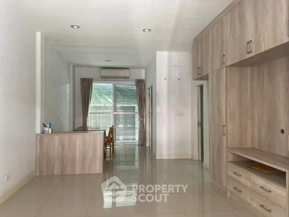 Spacious modern living room with sleek wooden furniture and large windows for natural light.