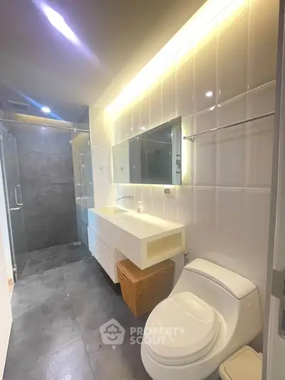 Modern bathroom with sleek design, featuring a spacious shower and elegant lighting.