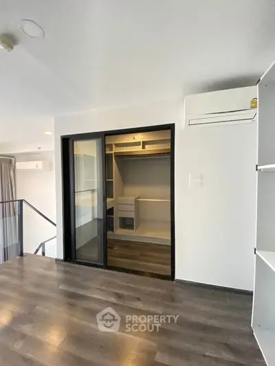 Modern interior with sleek wooden flooring and built-in closet, featuring air conditioning for comfort.