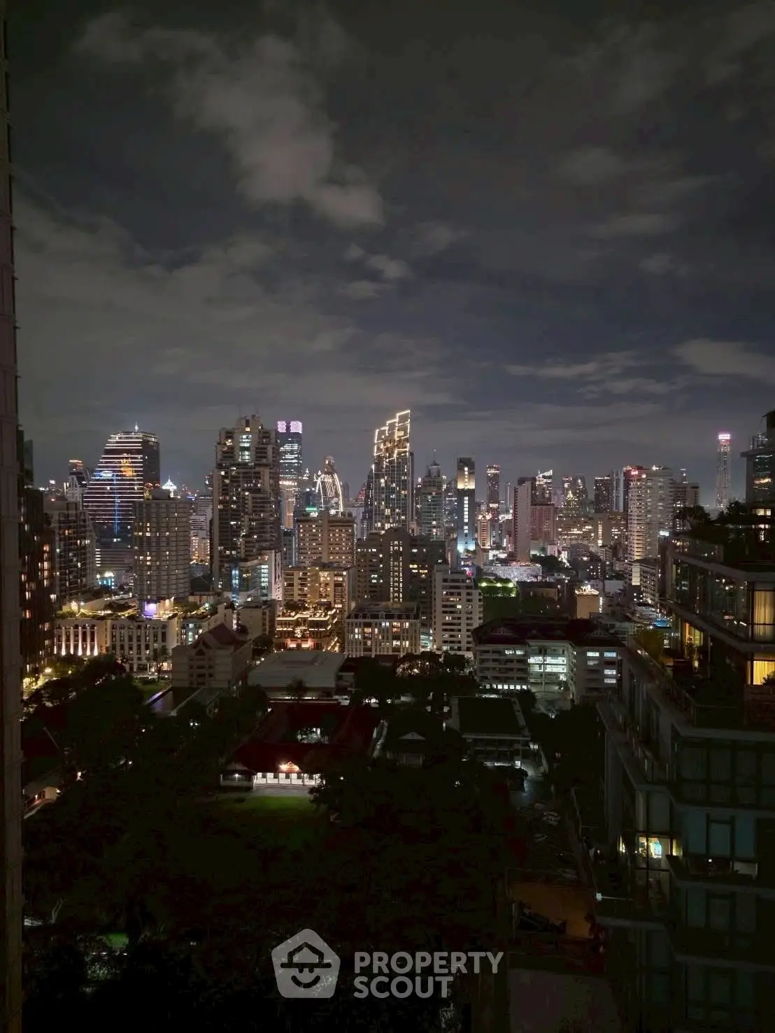 Stunning city skyline view from a high-rise building at night, showcasing vibrant urban lights.
