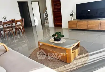 Spacious modern living room with sleek furniture and large TV, perfect for relaxation and entertainment.