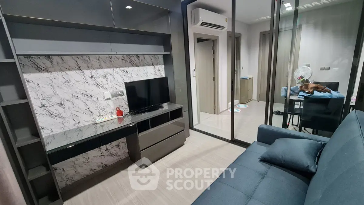 Modern living room with marble accent wall and sleek furniture in a stylish apartment.