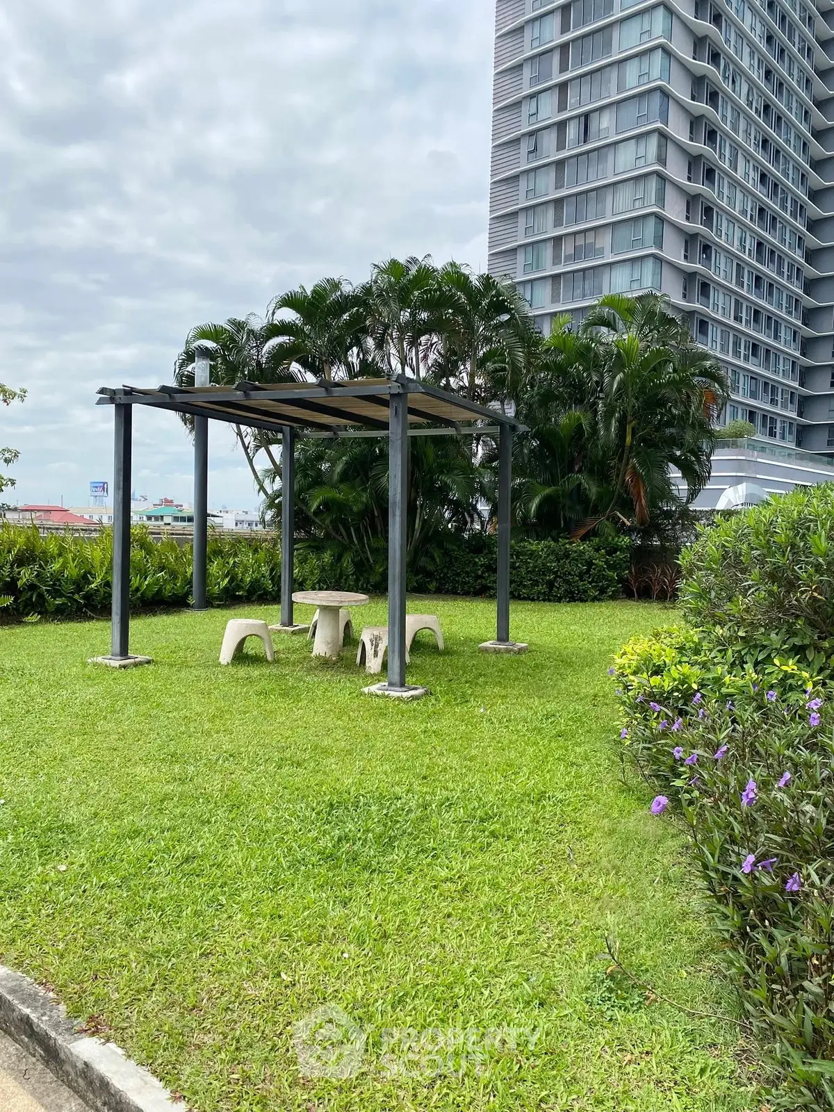 Modern high-rise building with lush garden and seating area, perfect for relaxation.