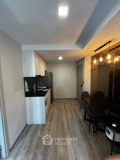 Modern kitchen with sleek design and dining area featuring stylish lighting fixtures.