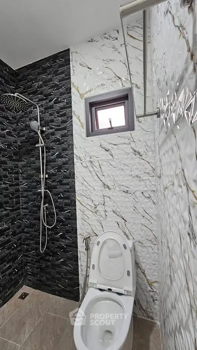 Modern bathroom with stylish black and white tile design and rainfall showerhead.