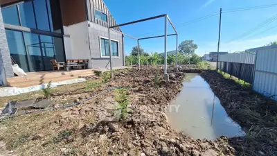 Modern house exterior with garden space and water feature under construction