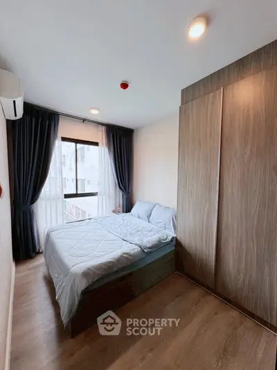 Cozy bedroom with large window and wooden wardrobe in modern apartment