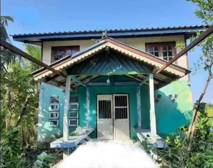 Charming two-story house with rustic design and lush greenery, perfect for serene living.