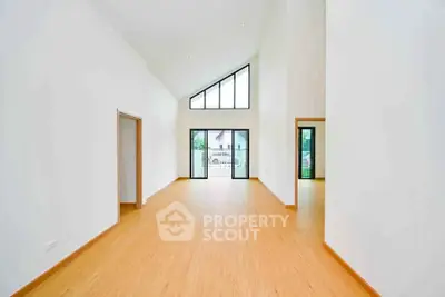 Spacious modern living room with high ceilings and large windows offering natural light.