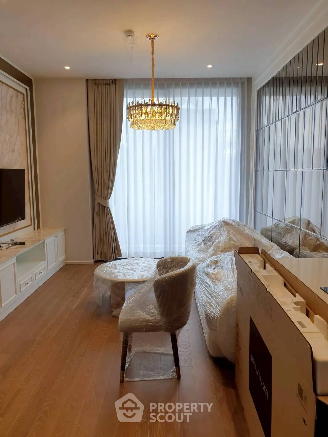 Elegant living room with chandelier and floor-to-ceiling windows in modern apartment