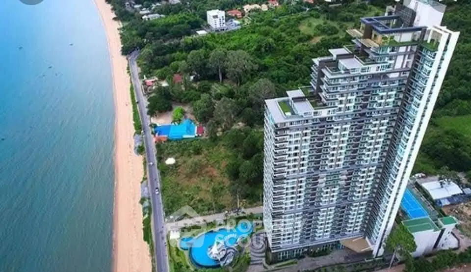 Stunning beachfront high-rise building with panoramic ocean views and lush greenery.