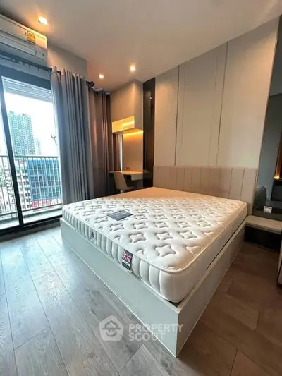 Modern bedroom with large window and city view, featuring stylish decor and ample natural light.