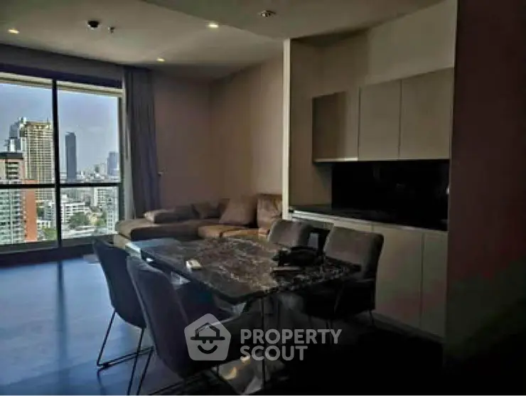Modern living room with city view and sleek kitchen area in high-rise apartment.