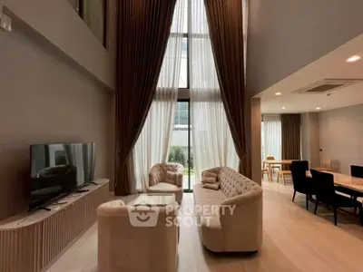 Luxurious high-ceiling living room with elegant furniture and large windows.