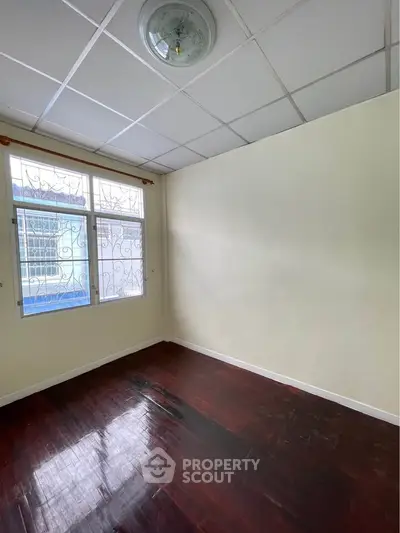 Spacious empty room with wooden floors and large window, perfect for customization.