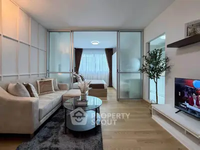 Modern living room with cozy sofa, glass partition, and elegant decor in a stylish apartment.