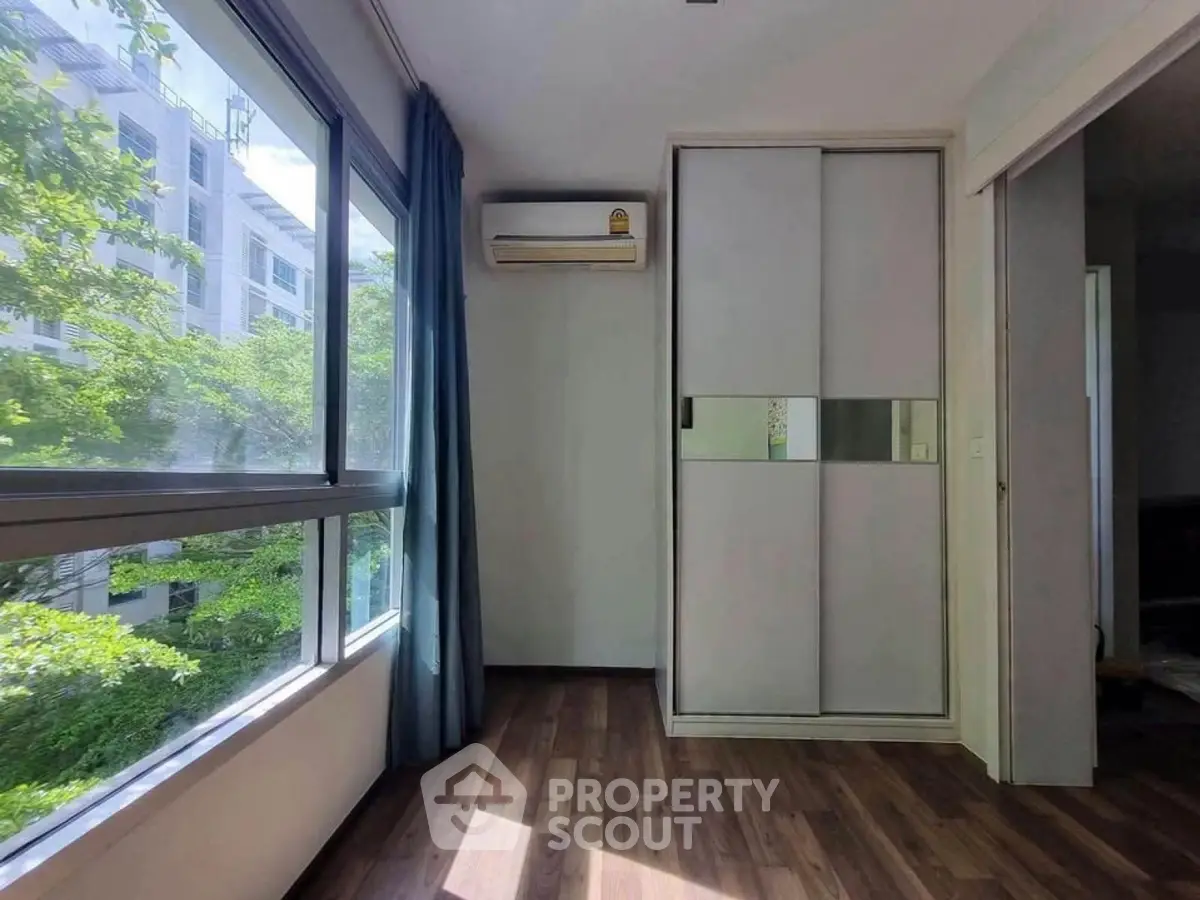 Bright bedroom with large window and air conditioning, featuring modern sliding closet doors.