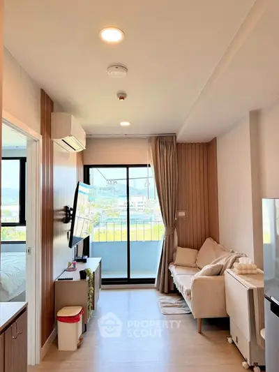 Modern living room with balcony view, featuring cozy sofa and wall-mounted TV in a stylish apartment.