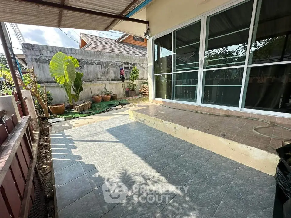 Charming patio with sliding glass doors and garden view, perfect for outdoor relaxation and entertaining.