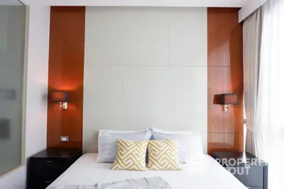 Modern bedroom with a large comfortable bed, stylish orange accents, and elegant bedside lighting, perfect for relaxation and tranquility.