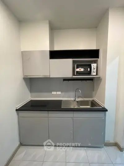 Modern compact kitchen with sleek cabinetry and built-in microwave