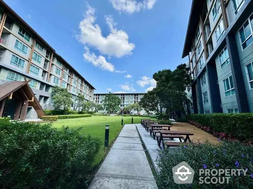 Modern apartment complex with lush garden and outdoor seating area