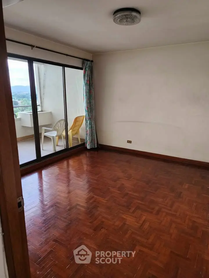 Spacious empty room with parquet flooring and balcony access, ideal for customization.