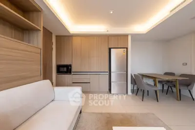 Modern open-plan living room with sleek kitchen and dining area, featuring contemporary furniture and neutral tones.