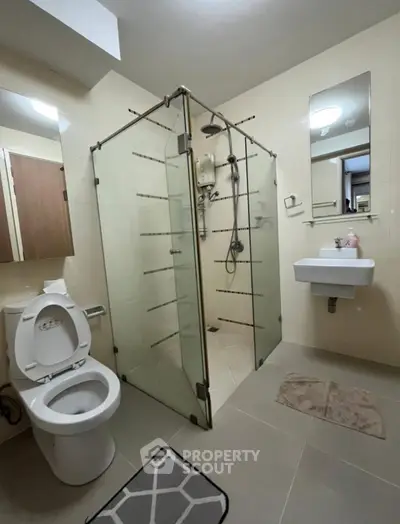 Modern bathroom with glass shower enclosure and sleek fixtures.
