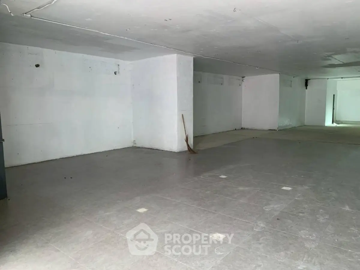 Spacious unfinished basement with tiled flooring, ideal for storage or renovation.