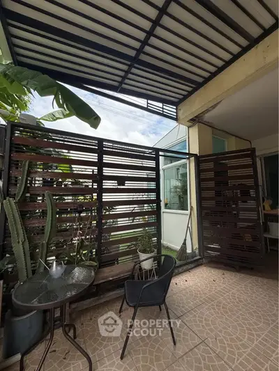 Charming patio with modern design, featuring a cozy seating area and lush greenery, perfect for relaxation.