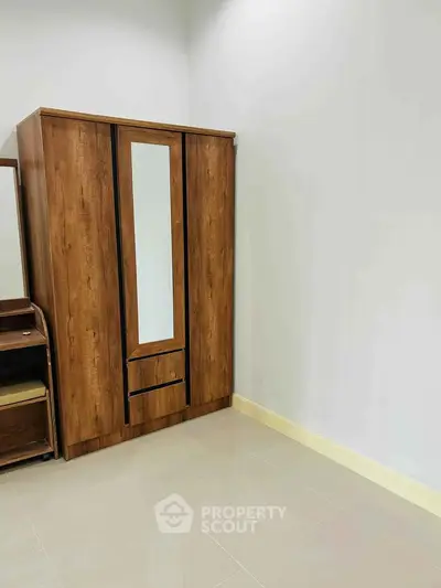Spacious bedroom with elegant wooden wardrobe and sleek tiled flooring.