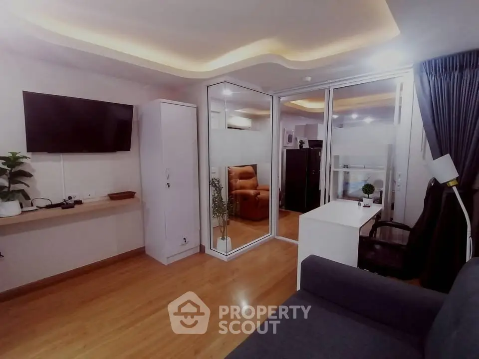 Modern living room with sleek design, featuring a TV, stylish lighting, and a cozy seating area.