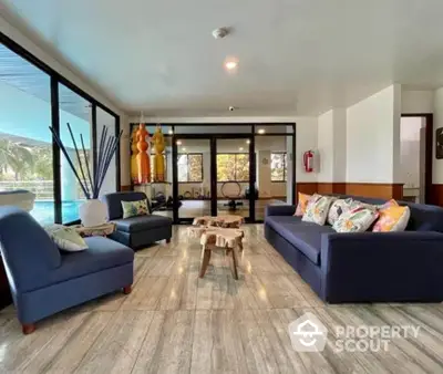 Spacious living room with modern decor and pool view, perfect for relaxation and entertaining.