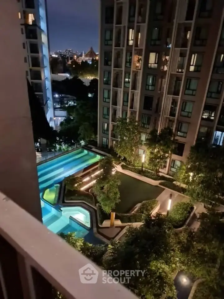 Stunning night view of modern apartment complex with illuminated pool and lush garden.