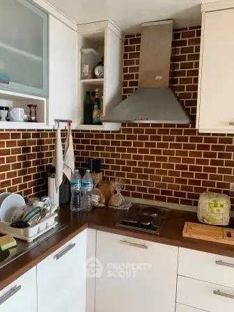 Modern kitchen with brown brick backsplash and stainless steel range hood