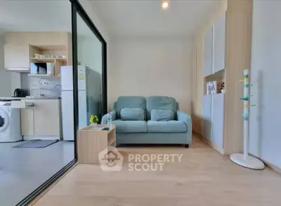 Modern living room with open kitchen, featuring sleek furniture and appliances, perfect for urban living.