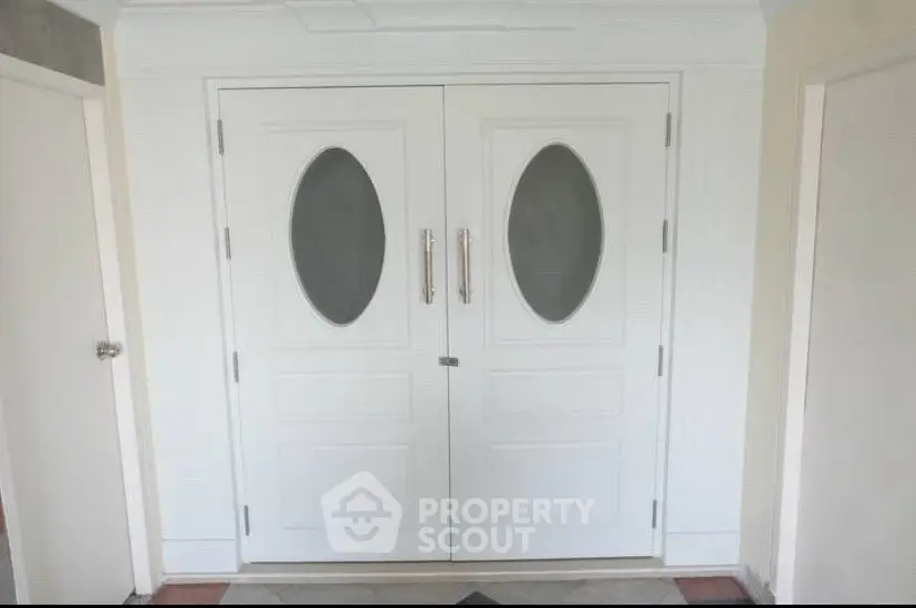 Elegant white double doors with oval glass panels in a modern entranceway.
