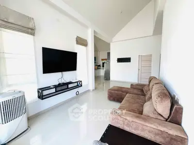 Spacious modern living room with plush sectional sofa and wall-mounted TV, featuring high ceilings and sleek design.