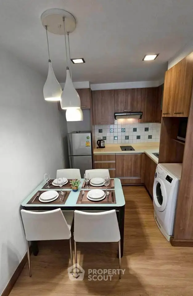 Modern kitchen with dining area, featuring wooden cabinets and washing machine.