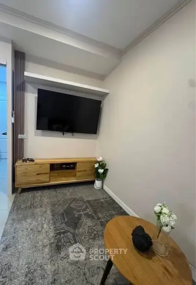 Modern living room with wall-mounted TV and stylish wooden furniture, perfect for cozy entertainment.