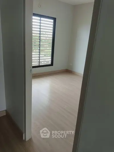 Minimalist empty room with wooden flooring and large window