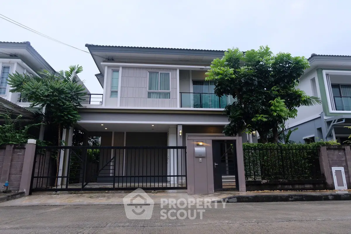 Modern two-story house with gated entrance and lush greenery