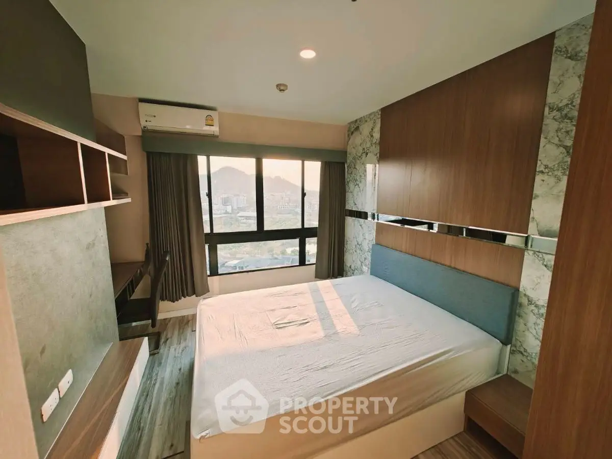 Modern bedroom with large window and scenic view, featuring stylish wood paneling and built-in storage.