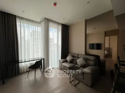 Modern living room with sleek furniture and large windows offering city views.
